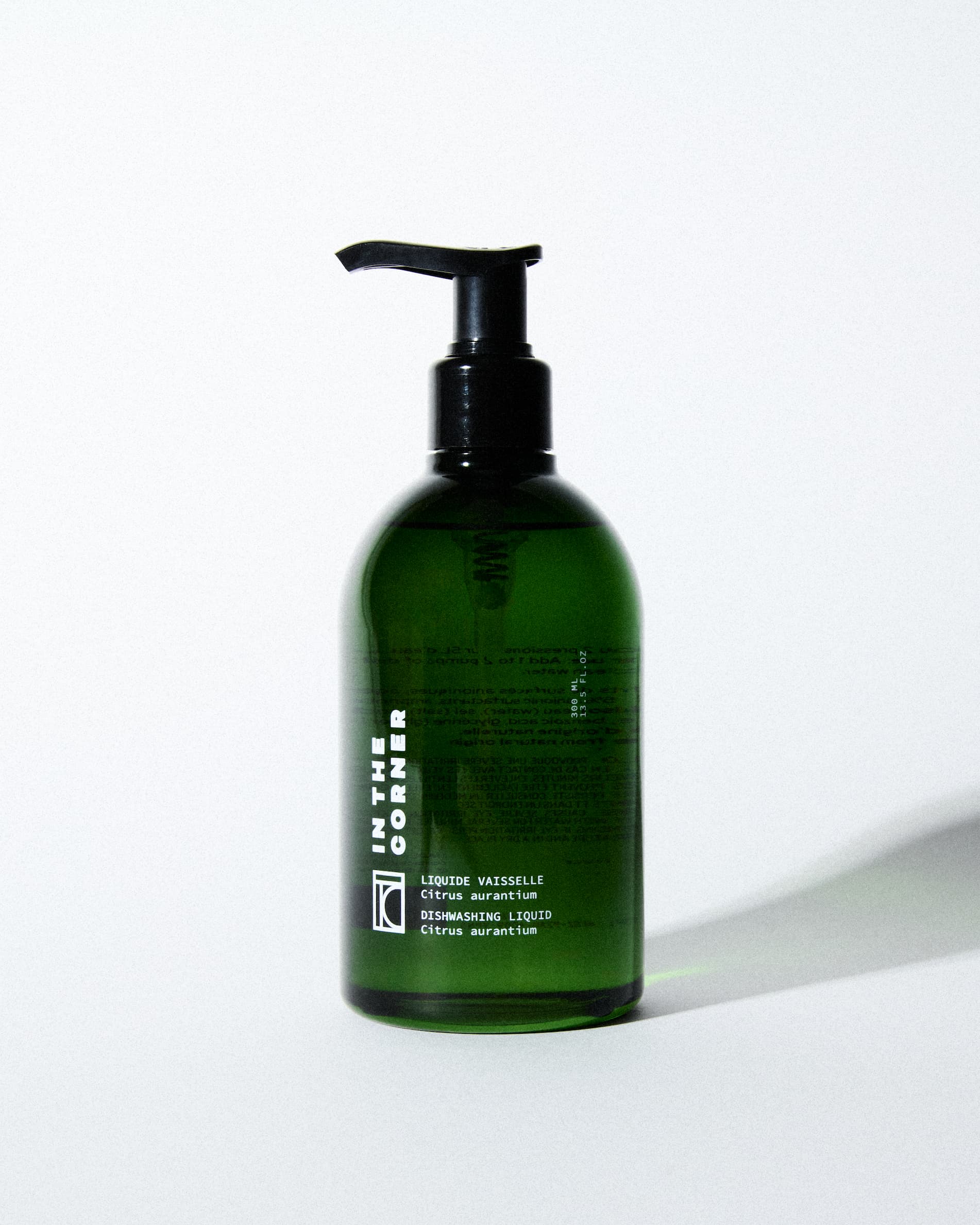 Liquide vaisselle au parfum signature Citrus Aurantium pour votre cuisine, dans une jolie bouteille en verre verte, présentée sur un fond blanc
