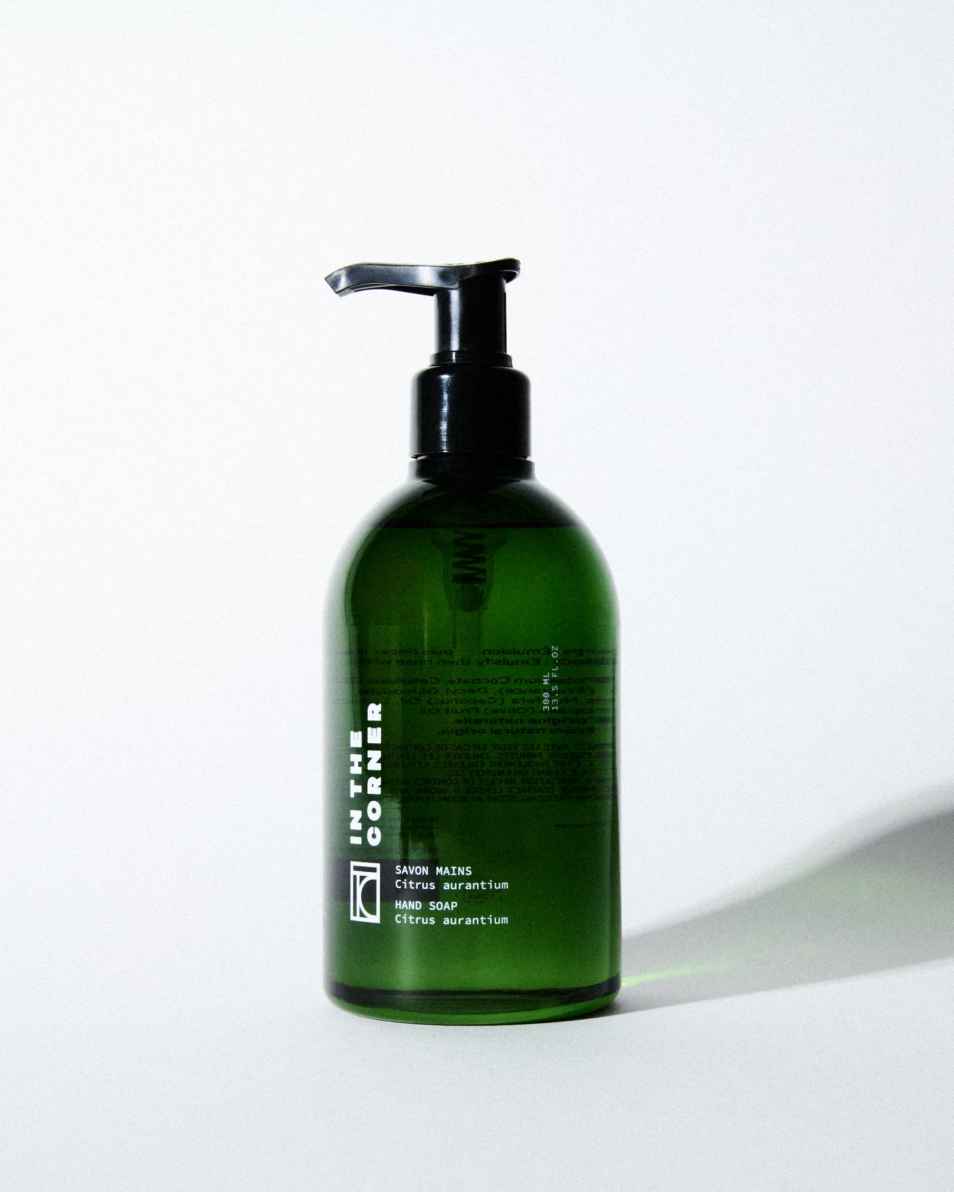 Savon mains au parfum signature Citrus Aurantium pour les mains et le corps, dans une jolie bouteille en verre verte, présentée sur un fond blanc